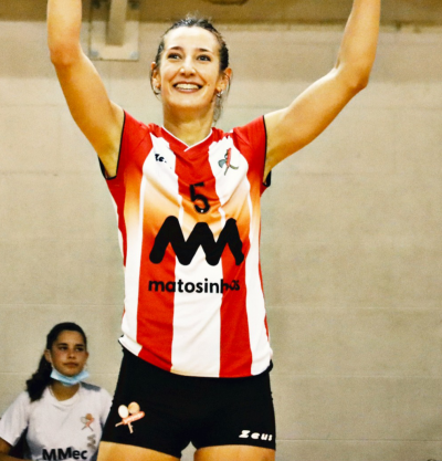 Jovem mulher com camisola de voleibol vermelha, branca e preta e calções pretos