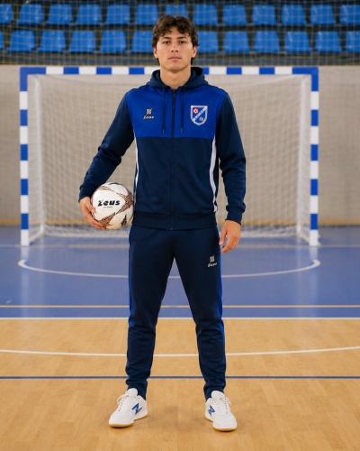 Homem com fato de treino azul e bola de futsal em pavilhão