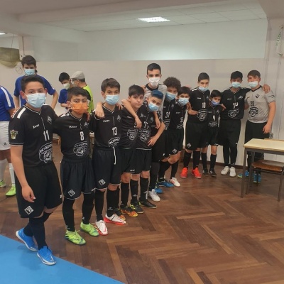 Crianças com uniformes desportivos pretos alinhadas numa sala interior