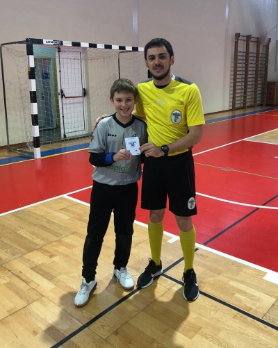 Dois rapazes num pavilhão desportivo, um com camisa cinza e outro com camisa amarela e calções pretos