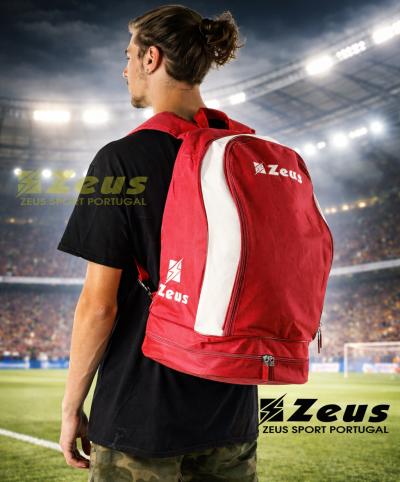 Mochila vermelha e branca da marca Zeus usada em campo de futebol