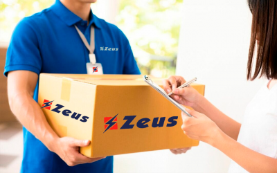 Empregado de entrega com uniforme azul a segurar caixa Zeus enquanto cliente assina clipboard