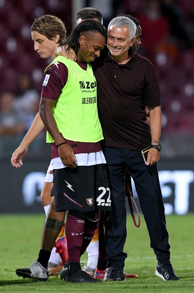 Jogador de futebol e treinador no campo de jogo à noite