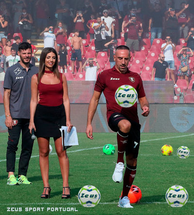Três pessoas no campo de futebol com bolas e logótipos da ZEUS
