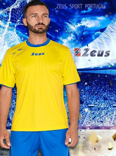 T-shirt desportiva amarela com gola azul e logotipo Zeus, cenário de estádio de futebol