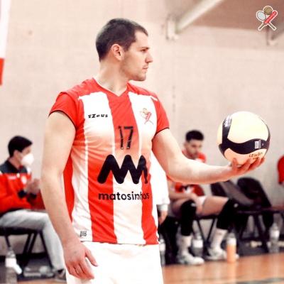 Jogador de voleibol com uniforme vermelho e branco segurando uma bola