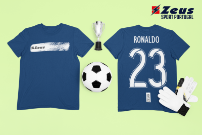 Duas t-shirts azuis Zeus, bola de futebol, luvas de guarda-redes e troféu num fundo verde claro