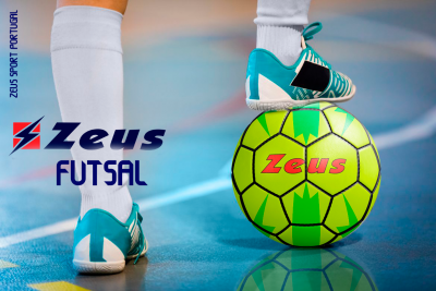 Pessoa com sapatilhas azul turquesa a apoiar bola de futsal verde amarela com texto Zeus em campo indoor