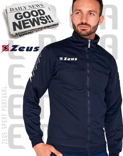 Homem com casaco desportivo azul escuro com logo 'Zeus' e texto 'Zeus Sport Portugal' no fundo e jornal 'DAILY NEWS GOOD NEWS!!'