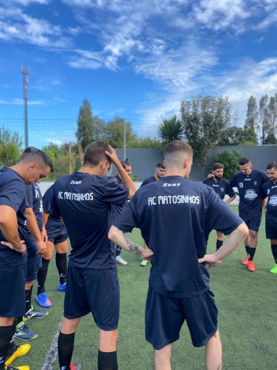 Jogadores de futebol com uniformes azuis escuros AC MATOSINHOS em campo de relva