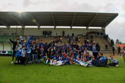 Equipa de futebol em campo com bancadas cobertas ao fundo