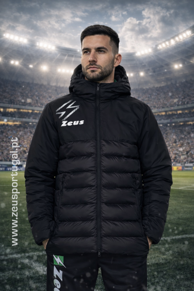 Homem com casaco acolchoado preto e logotipo Zeus num estádio de futebol