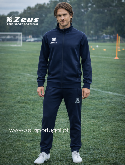 Homem com fato de treino azul escuro e logótipo Zeus branco em campo de futebol