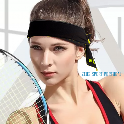 Mulher com faixa preta na cabeça segurando raquete de ténis e usando top desportivo