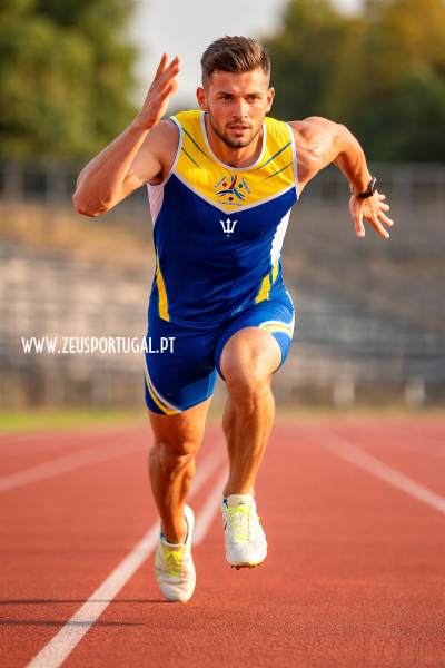 Atleta a correr com fato de corrida azul e amarelo numa pista desportiva