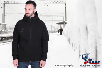 Homem a usar casaco preto com capuz da Zeus em estação de comboios nevada