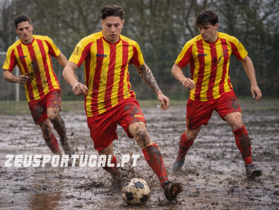 Jogadores de futebol com camisolas amarelas e vermelhas a jogar num campo lamacento