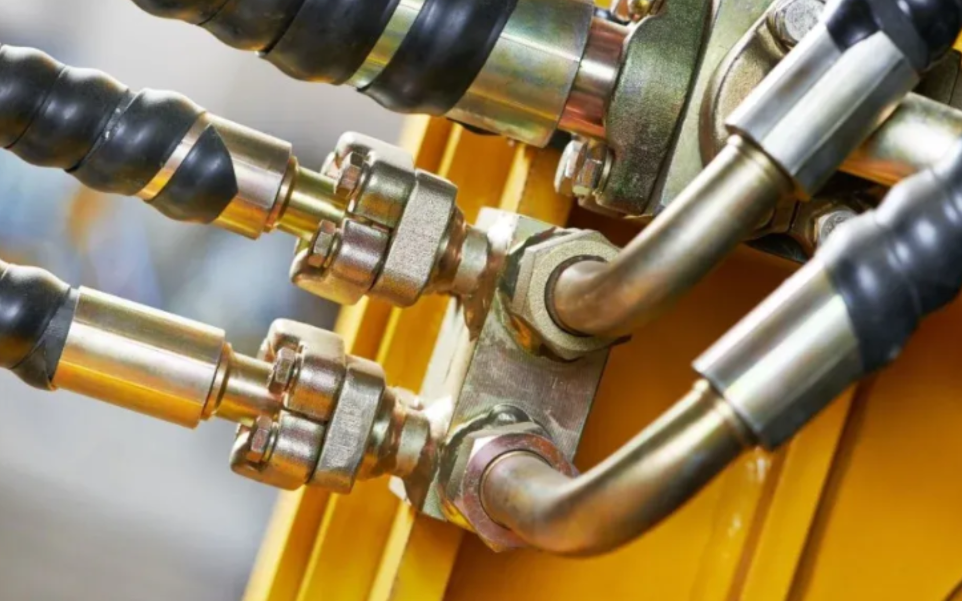 Tubagens metálicas com conexões e mangueiras pretas ligadas a suporte amarelo