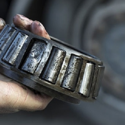 Mão segurando rolamento de metal com rolos cilíndricos