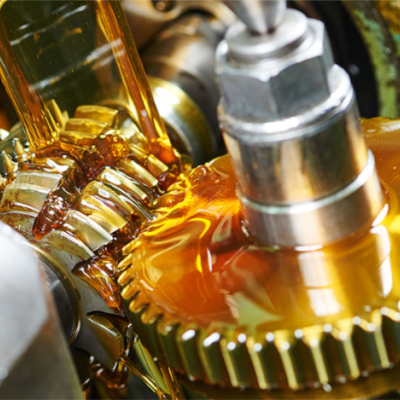 Engrenagens metálicas douradas com óleo lubrificante num ambiente industrial.