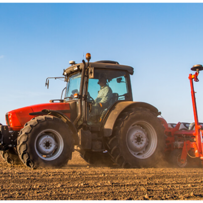 Trator agrícola vermelho com equipamento de sementeira num campo arado